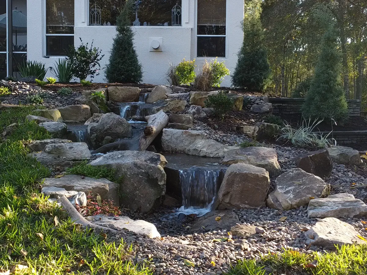 Finished backyard pondless waterfall with cascading streams and natural rock landscaping.