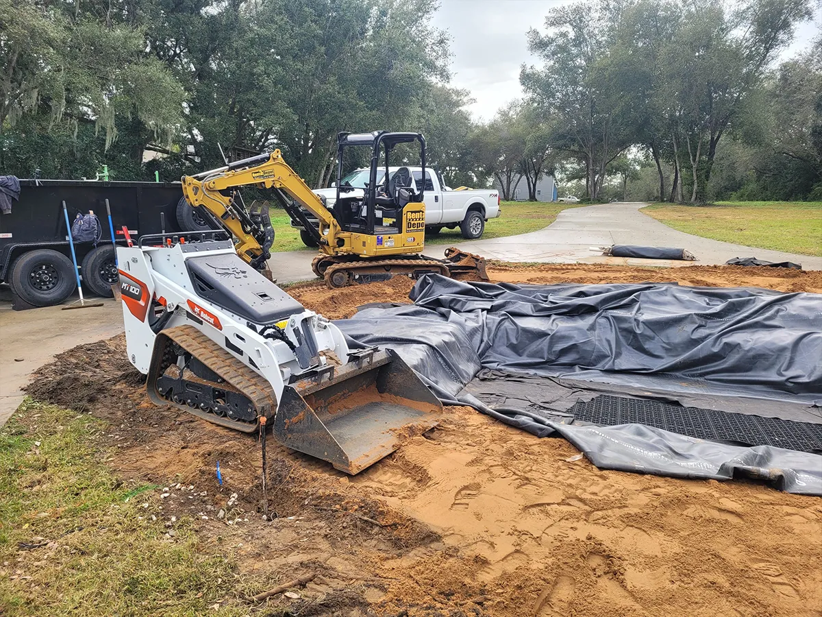 Excavation and groundwork for a large pondless fountain with construction equipment on site