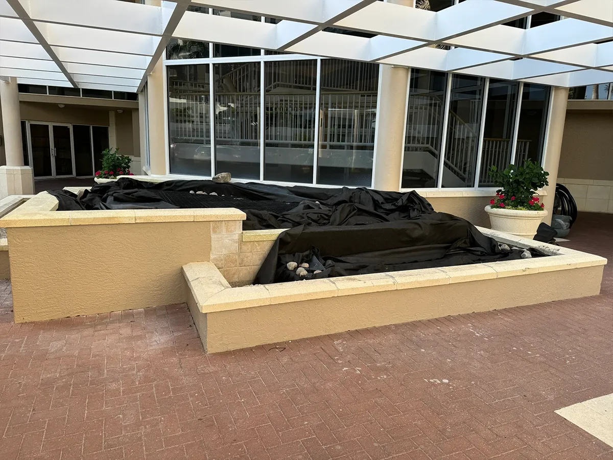 Commercial water feature installation in progress with protective covering over the area.