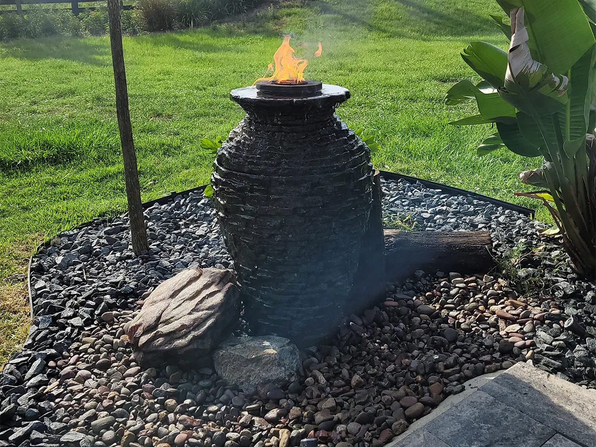 Backyard fountain feature with a stone jar and fire element for a unique water and fire display