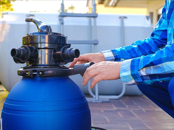 Worker adjusting pond filtration equipment, ensuring proper water flow and cleanliness for pond maintenance and upkeep.